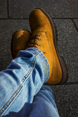 photo made of a man, in detail there are his shoes and crossed legs, he wears jeans
