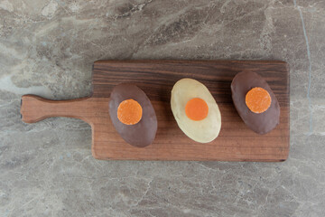 Three cakes with marmalades on wooden board