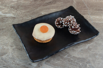 Cookie with marmalade and pinecones on black plate