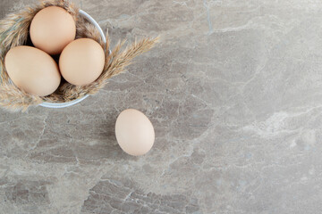 Bowl of raw eggs on marble background
