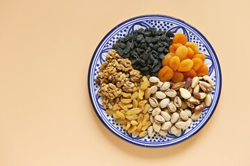 Nuts and dried fruits assortment on light pastel background. Natural energy source rich in vitamins and minerals. Flat layot