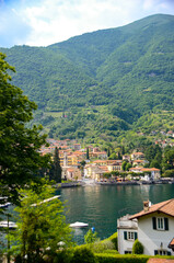 Fototapeta na wymiar Scenic view in Como lake, Italy with waterfront town and mountain in the back. Summer holidays and travel destinations in Europe for relaxation and romance