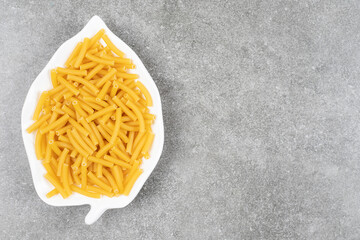 Heap of raw macaroni on white plate