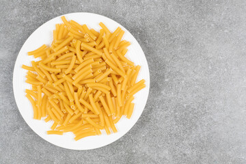 Pile of uncooked pasta on white plate
