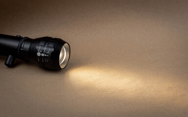 A bright beam of light from a flashlight shines on a brown recycled craft paper background