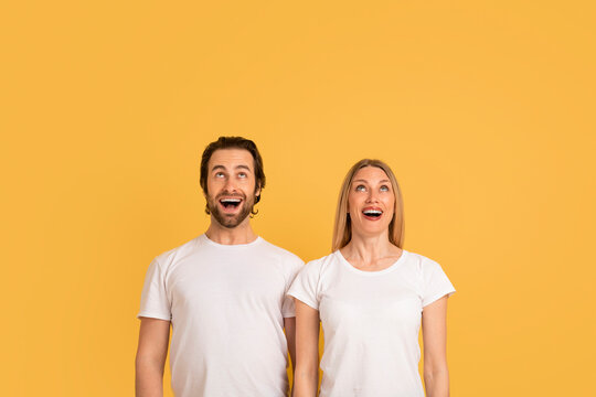 Emotions of great ad and offer. Shocked happy young caucasian woman and man in white t-shirts with open mouths