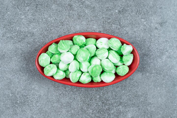 Hard green candies on red bowl