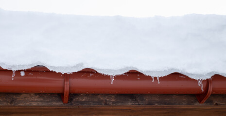 Snow falling from the roof of the house. Winter weather with heavy snowfall