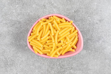 Heap of raw macaroni in pink bowl