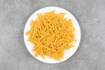 Pile of uncooked pasta on white plate