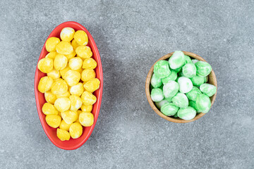 Two bowls of hard candies on marble surface