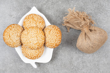 Biscuits with sesame seeds on white plate with sackcloth