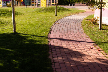 Cobblestone road in the park in autumn and green trees in background