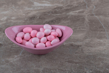 Fototapeta na wymiar Tasty gumballs in the bowl, on the marble background