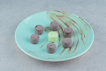 Assorted candies on the plate on the marble background