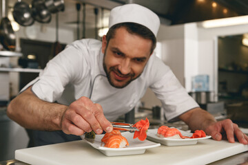 Sushi master prepares sushi for serving in modern commercial kitchen
