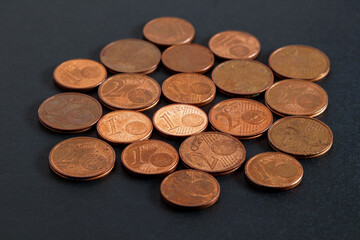 Scattered euro cent coins on a black table close-up. Small change, 1 and 2 cent coins. Soft focus