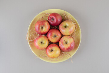 Apples and straw in a bowl on marble background
