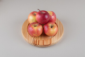 Small pile of apples on a wooden platter on marble background