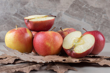 Plane tree leaves under a bundle of sliced and whole apples on marble background
