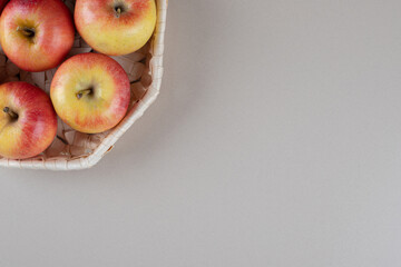 Apples in a white basket on marble background