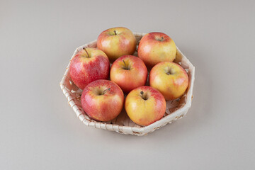 A bundle of apples in a basket on marble background