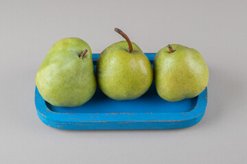 Blue platter with a handful of pears on marble background