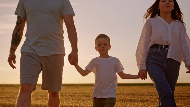 Preschooler boy enjoys spending weekend with parents in countryside at back sunset