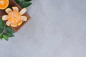 Peeled and sliced tangerines on a small board on marble background