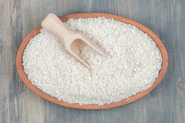 Healthy raw rice with wooden spoon on a wooden table