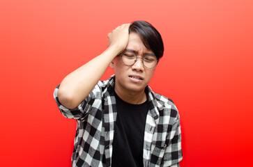 young asian man wearing glasses suffering from headache looking unbearable pain and miserable. headache concept.