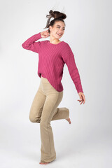 Beautiful long hair brunette woman portrait with purple sweater and beige tight trousers. Studio shot. Model with bare feet. Model looking aside the camera. Image contains motion blur and noise