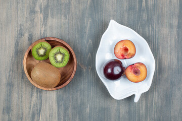 Fototapeta na wymiar Fresh sliced plums with juicy kiwi on a wooden table