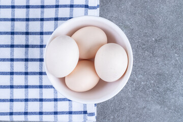 Fresh white chicken eggs on a white plate