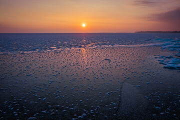 Sunrise and frozen sea. Beautiful winter landscape with lake and red sun in morning time. Daybreak