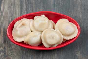 Delicious dumplings in a red plate on a wooden table