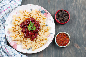 Delicious macaroni with beans and pepper on a wooden table