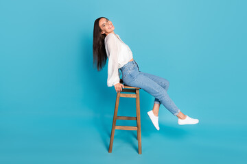 Full body profile portrait of stunning satisfied lady sit chair toothy smile isolated on blue color...