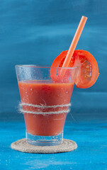 Flavorful tomato juice on the board, on the blue background