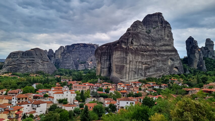 Fototapeta na wymiar Panoramic view of the peaceful tourist village Kastraki on a mystical cloudy day in Kalambaka, Meteora, Thessaly district, Greece, Europe. Surrounded by unique view of the giant cliffs and rocks.