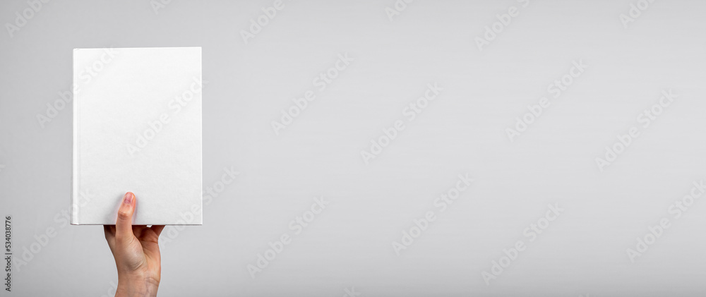 Poster white blank empty book mockup in hand on gray banner, background, copy space