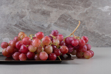 Red grapes on a small tray on marble background