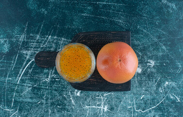  a display of a glass of processed juice and grapefruit on the blue background