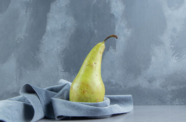 Pear standing upright on a piece of fabric on marble background © rastockinc