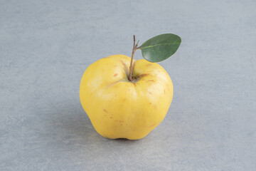 A single, leafy quince displayed on marble background