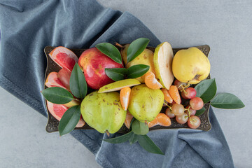 A generous serving of assorted fruits on a tray on marble background