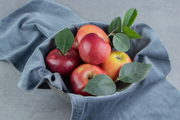 Small bundle of apples wrapped in a piece of cloth on marble background