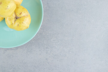 Small bundle of quinces on a cyan platter on marble background