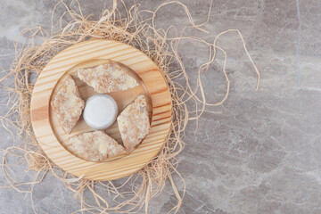 Cake slices around a vanilla powder coated cookie on a wooden plate on marble background