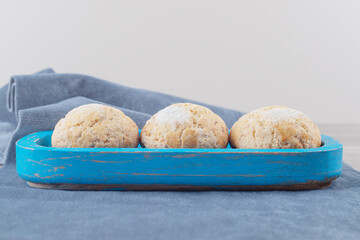Crumbly cookies on a blue platter on a piece of fabric on marble background